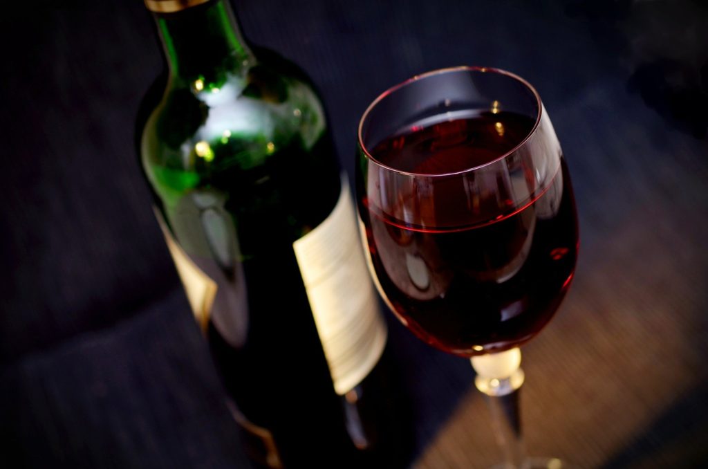 Rotweinflasche hinter einem gefüllten Weinweinglas