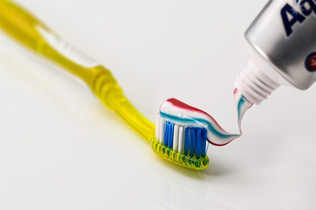 Gelbe Zahnbürste mit gestreifter Zahnpasta drauf