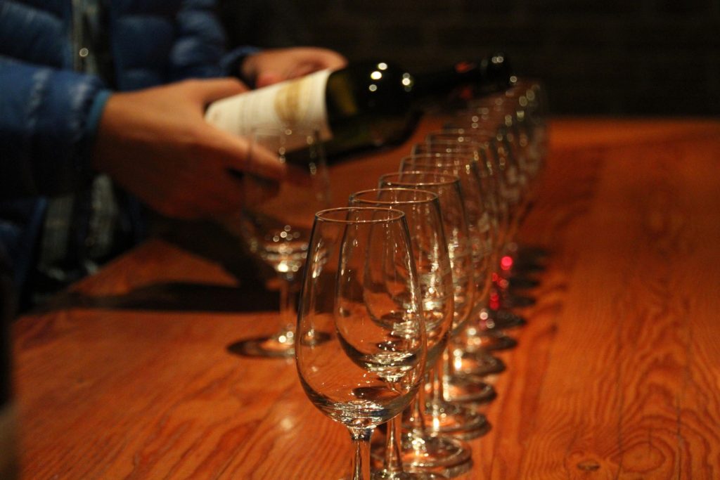 Leere Gläser in einer Reihe, die mit Wein befüllt werden.