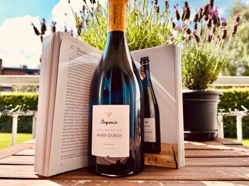 Champagner von Marie-Courtin vor einem Buch auf einem Balkontisch