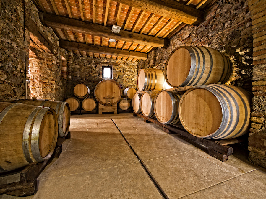 Weinfässer in unterschiedlichen Größen in einem Keller gestapelt