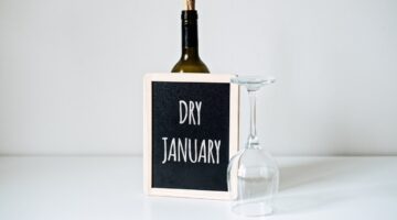 Flasche Wein und umgedrehtes Weinglas mit einer kleiner Kreidetafel, auf der Dry January steht