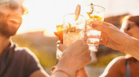 Bei Sonnenuntergang stoßen Freunde mit Longdrinks an