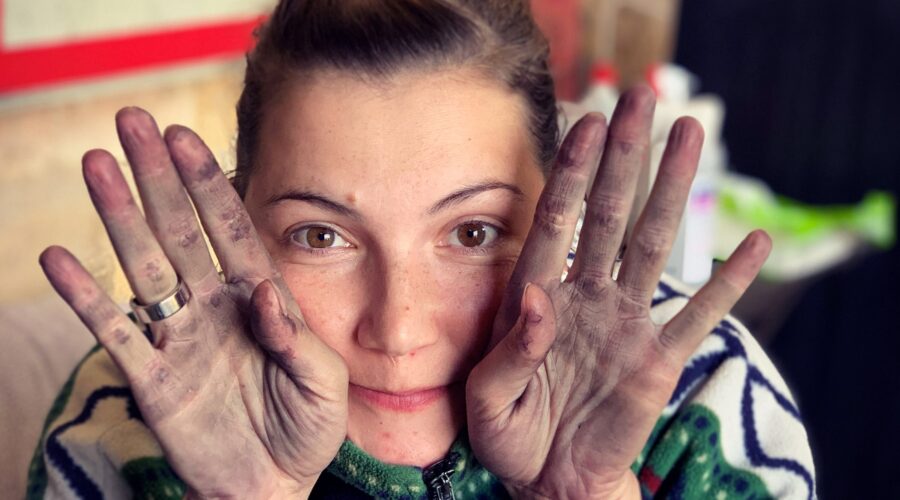 Winzerin Nea Berglund hält ihre von roten Trauben verfärbten Hände in die Kamera