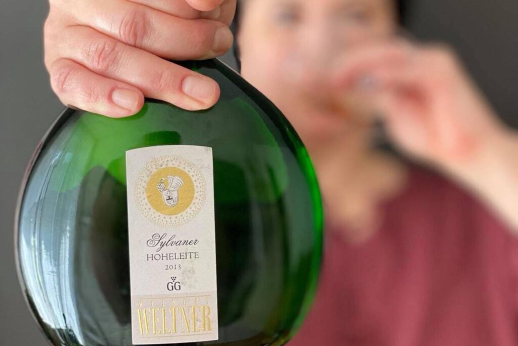 Frau hält Bocksbeutel mit dem Sylvaner Hoheleite vom Weingut Weltner in die Kamera