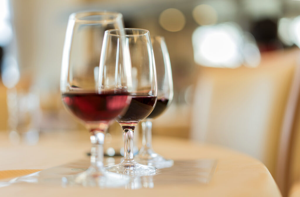 Drei Weingläser mit Rotwein unterschiedlicher Farbintensität in einer Reihe hintereinander
