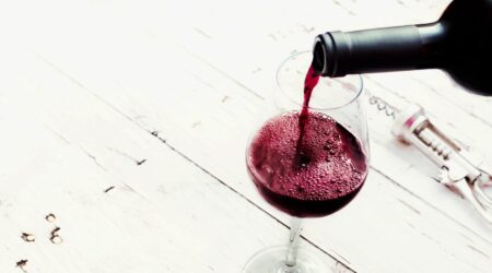 Cape Blend Rotwein einschenken in ein Glas auf einem weißen Holztisch